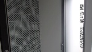 Un baño con piso estampado, un felpudo negro en la entrada y una puerta blanca.