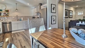 Une cuisine moderne avec des meubles blancs, une table à manger en bois et un lustre.