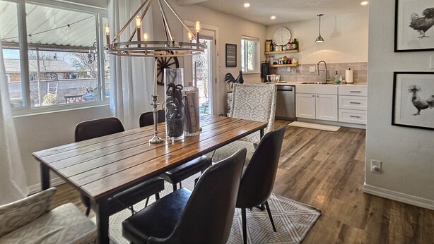 Un espace repas avec une table en bois, des chaises noires et un luminaire suspendu.