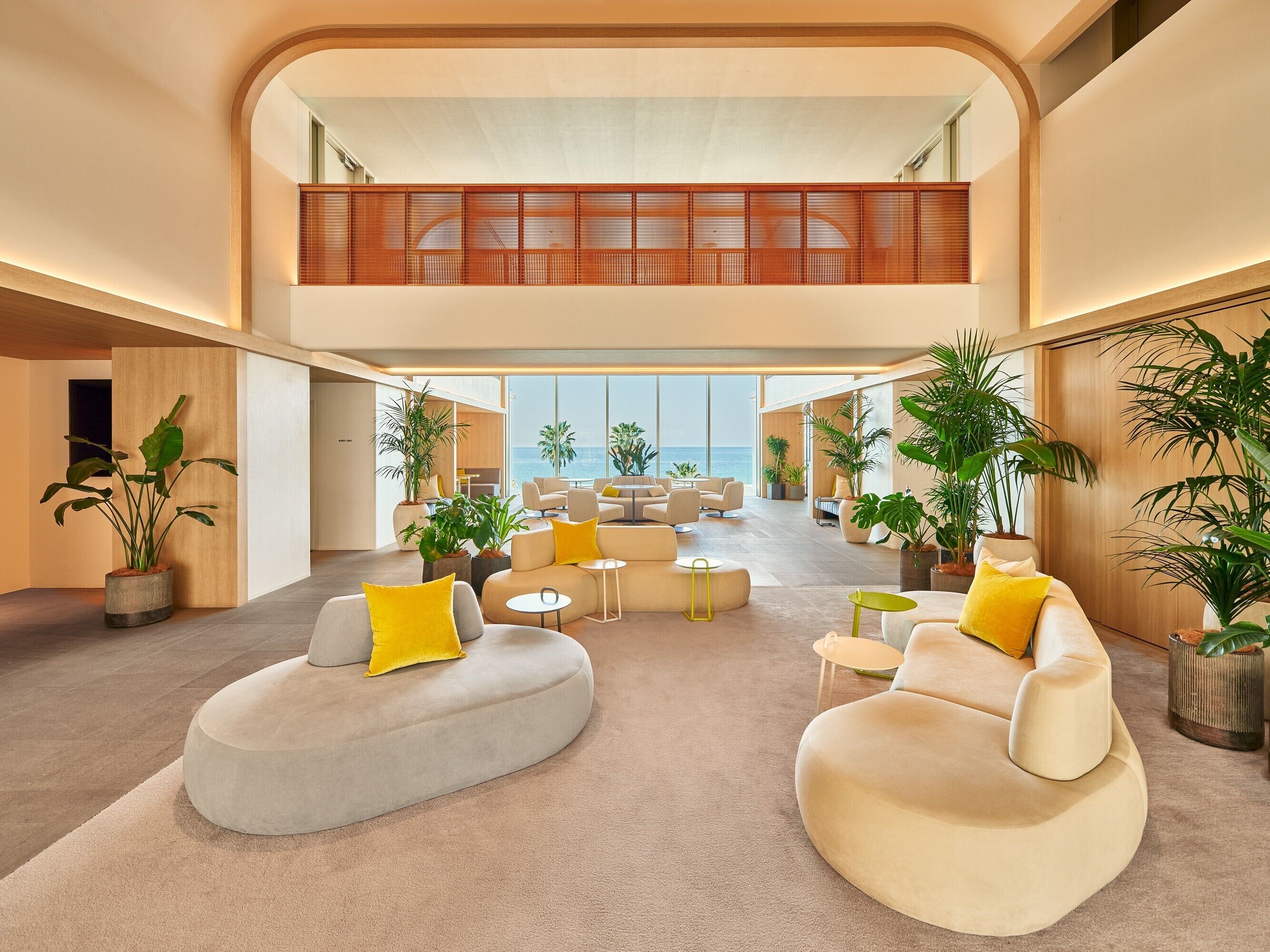 A spacious, modern lounge with a high ceiling, large windows, and a mezzanine level.