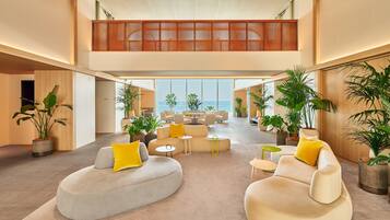 A spacious, modern lounge with a high ceiling, large windows, and a mezzanine level.