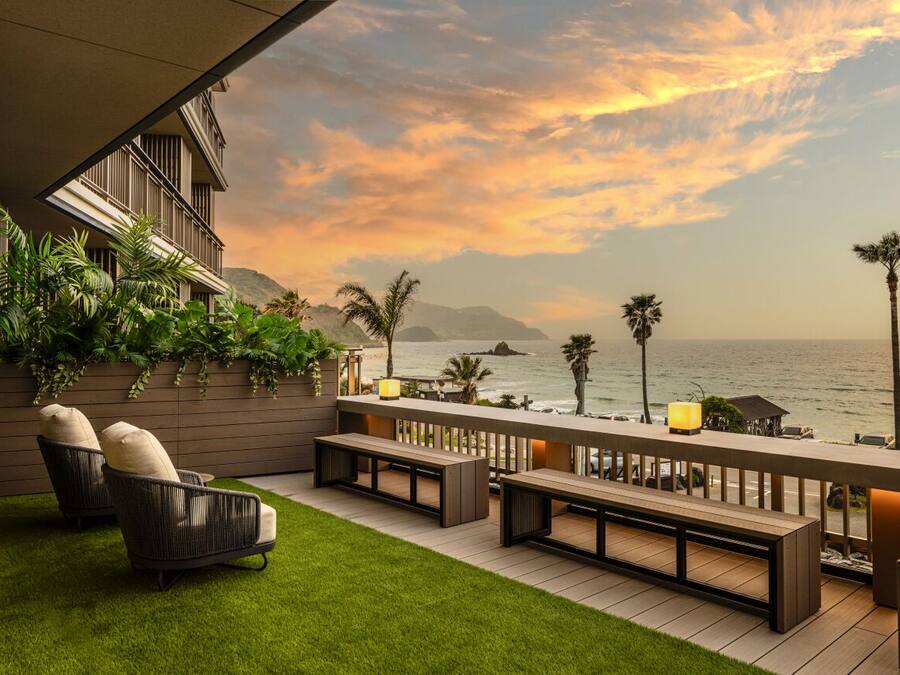 A deck with seating and a view of the ocean at sunset.