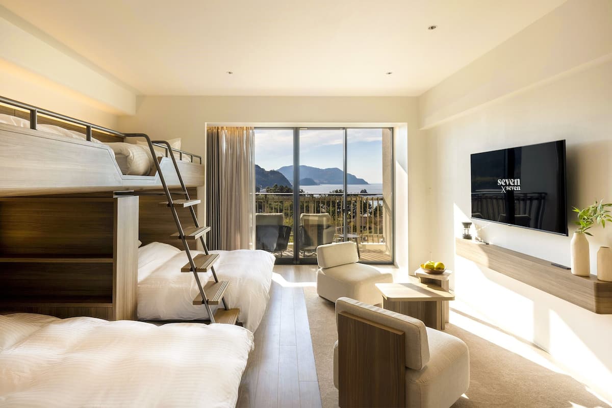 A modern hotel room with a balcony, a TV, and a bed with a ladder.