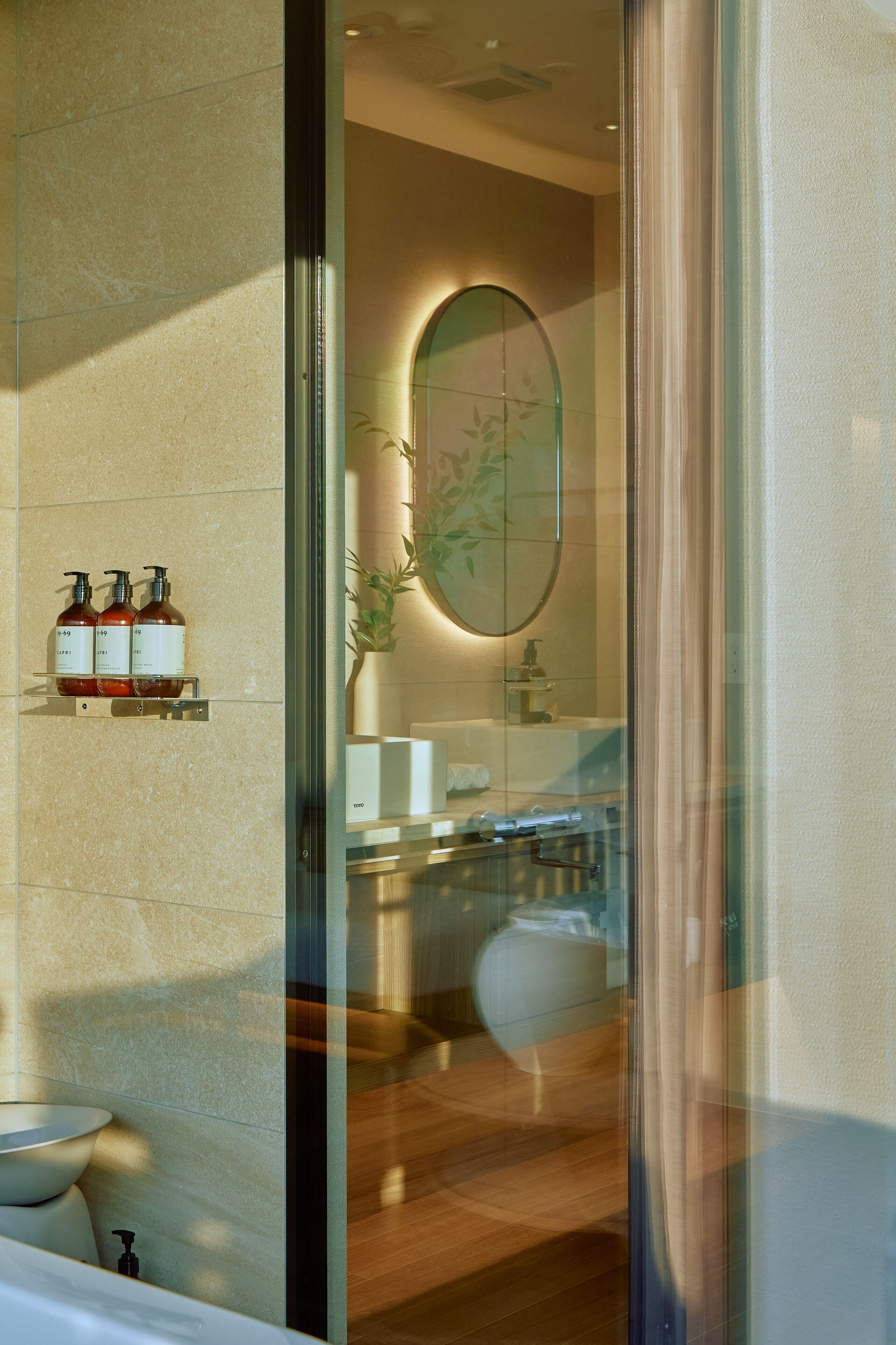 Un baño moderno con un espejo grande, un lavamanos y dos botellas de champú en una estantería.