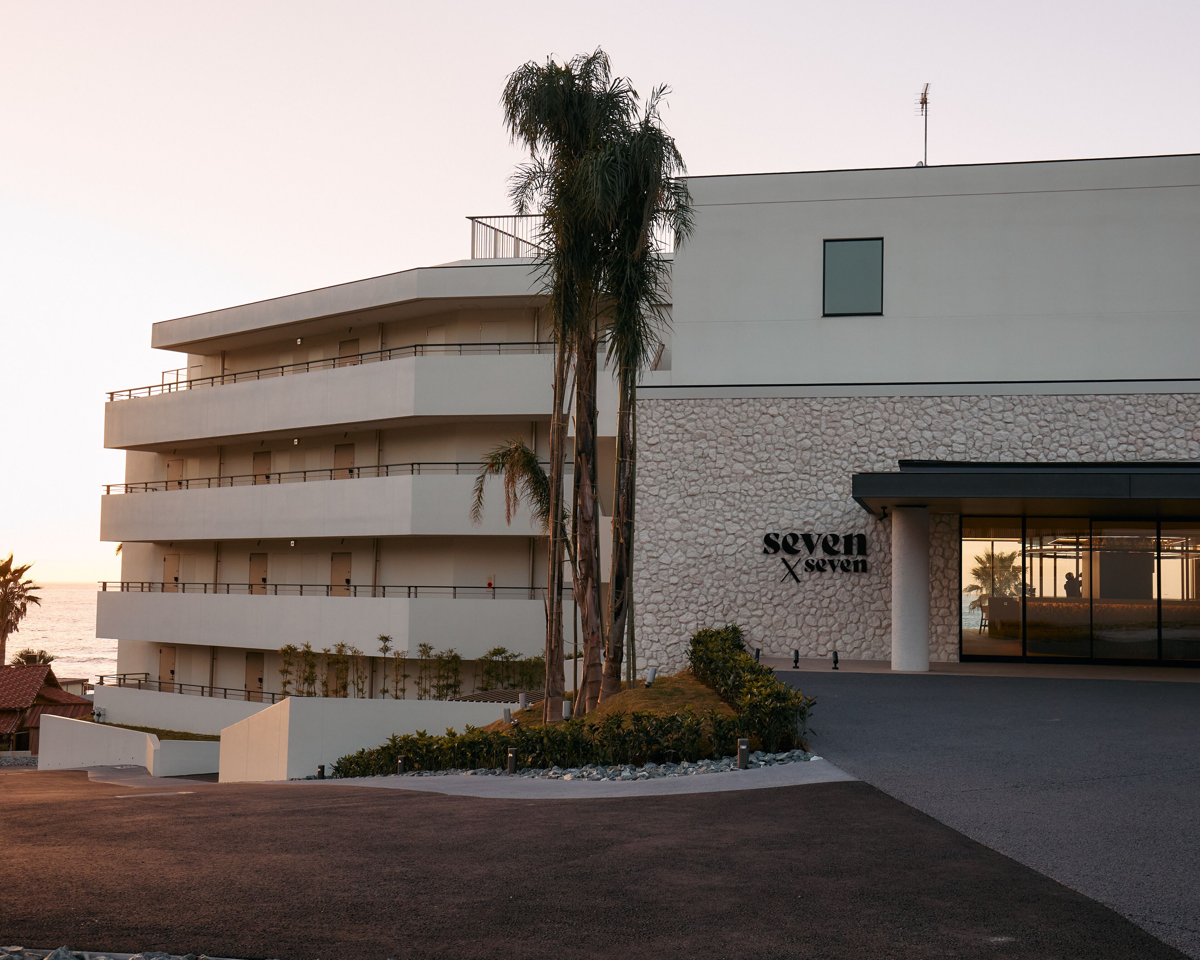 A multi-story hotel with a stone facade and a palm tree in the foreground.