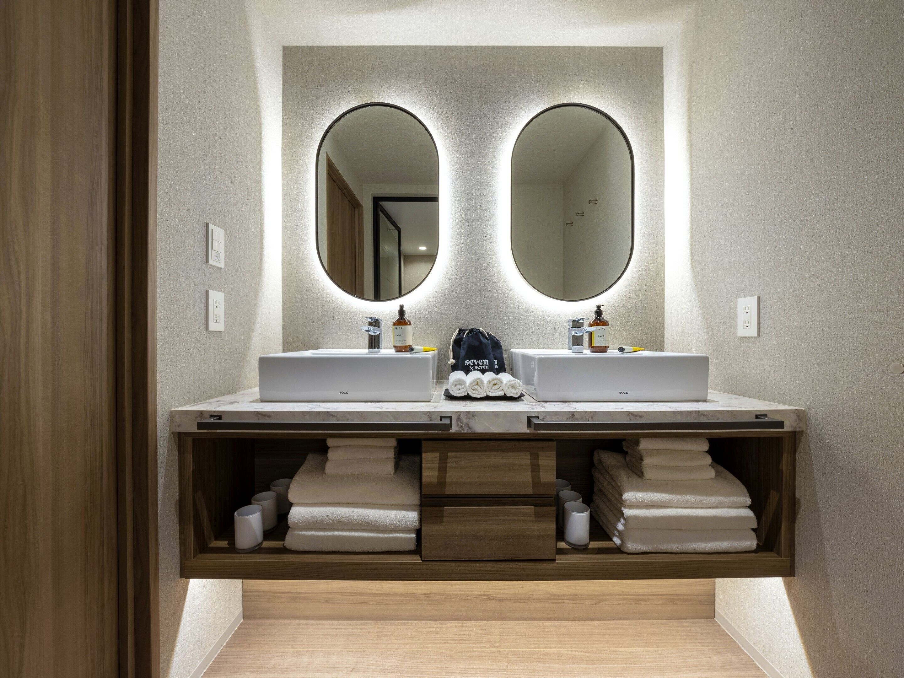 A modern bathroom with two sinks, a mirror, and a towel rack.