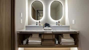 A modern bathroom with two sinks, a mirror, and a towel rack.