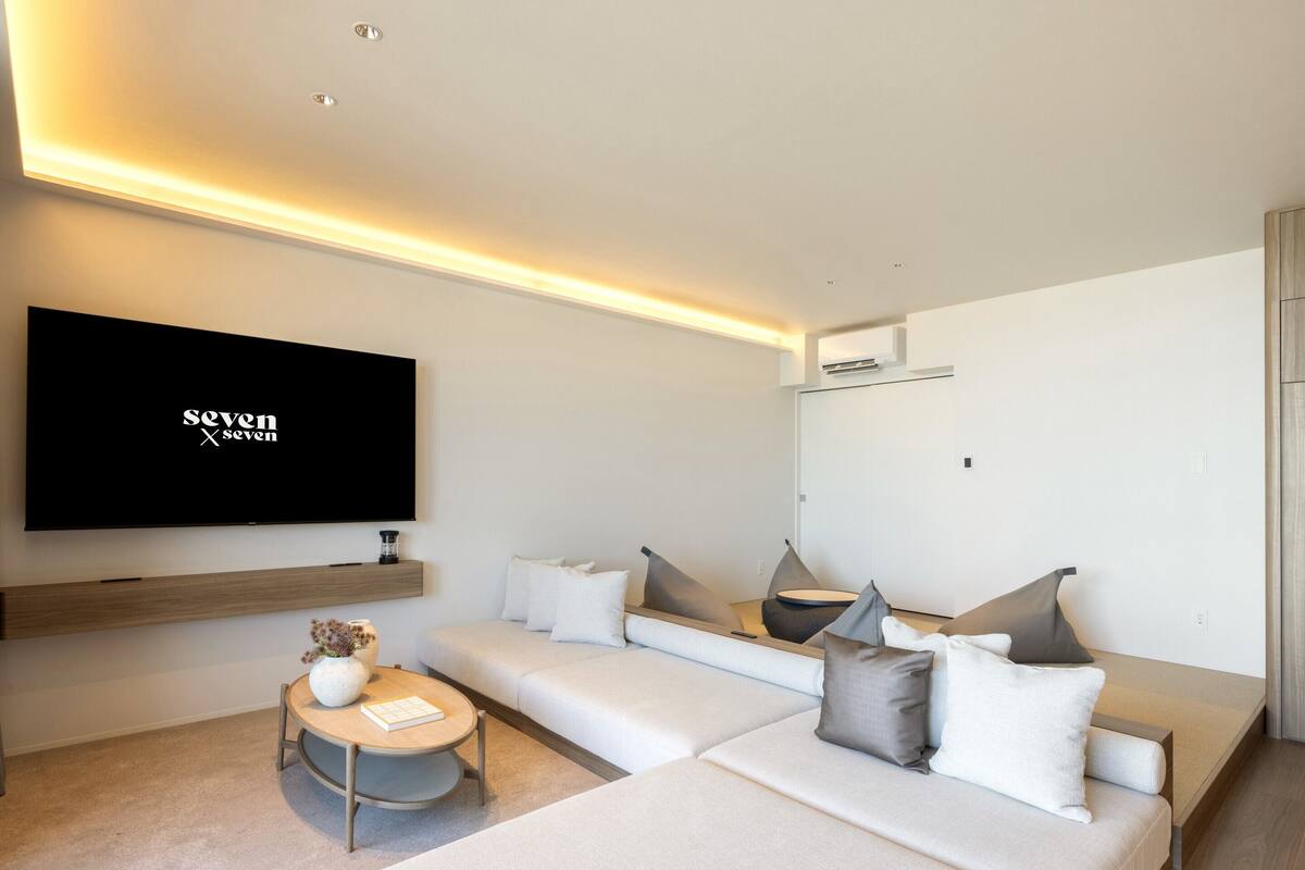 A modern living room with a large flat-screen TV, a sofa, and a coffee table.