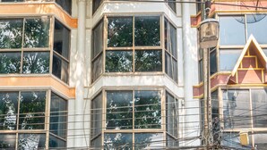 A building with multiple windows, a balcony, and a storefront with a sign indicating 'FREE JOINT'. - Blue Dream Guesthouse (Chiang Mai)