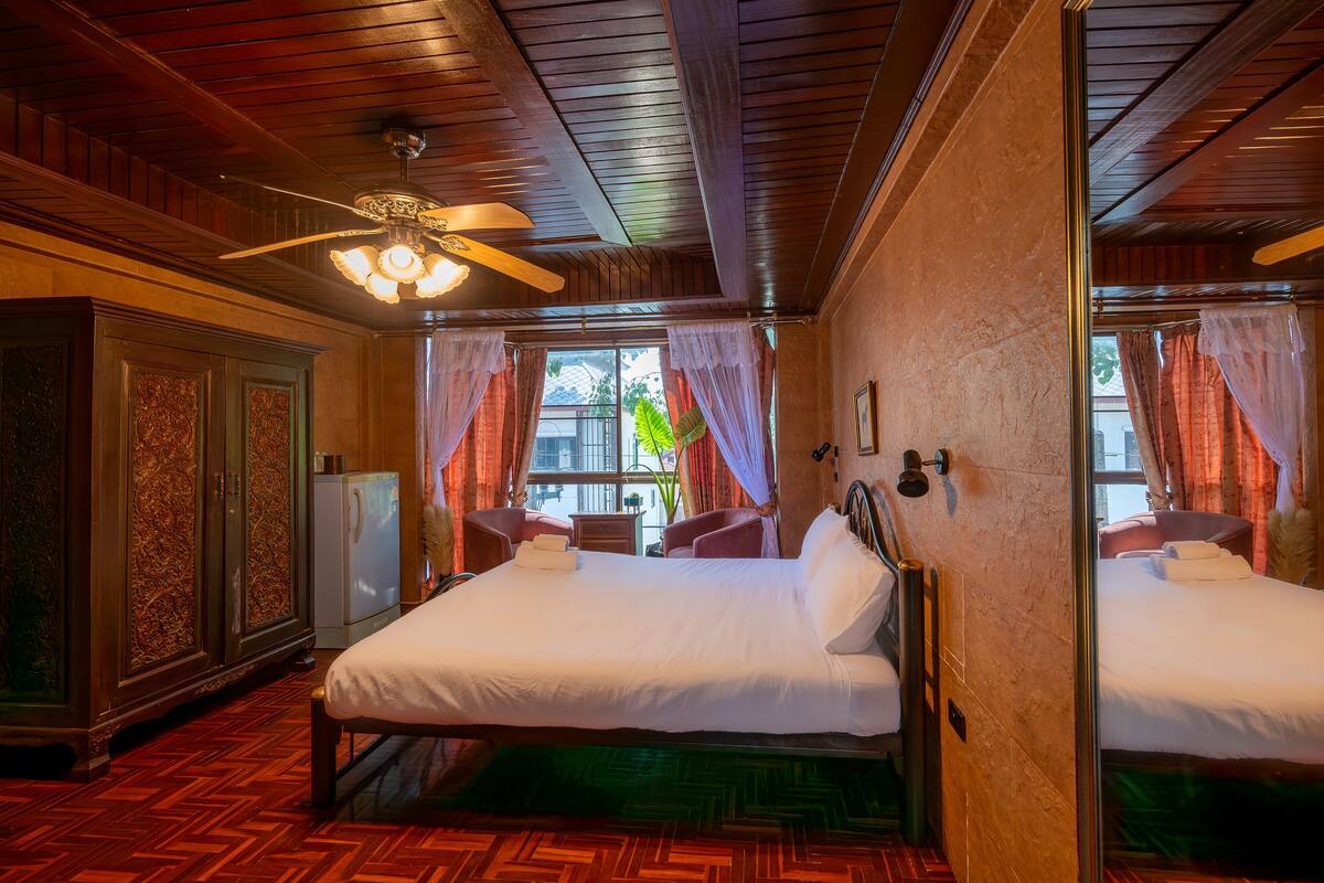Une chambre d’hôtel avec un grand lit, un ventilateur de plafond et une vue sur l’extérieur.