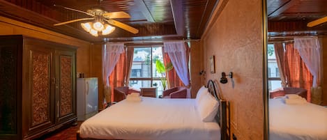 A hotel room with a large bed, a ceiling fan, and a view of the outdoors.