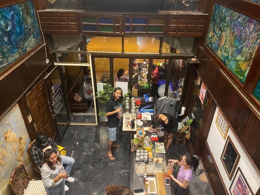 Um mercado interno movimentado com diversos quiosques de comida e uma área central para sentar.