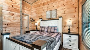 A wooden-paneled bedroom with a bed, bedside tables, and a window with blinds. - Great Location/Close to Dollywood/HotTub/Arcade/Mountain View/Dog Friendly (Sevierville)