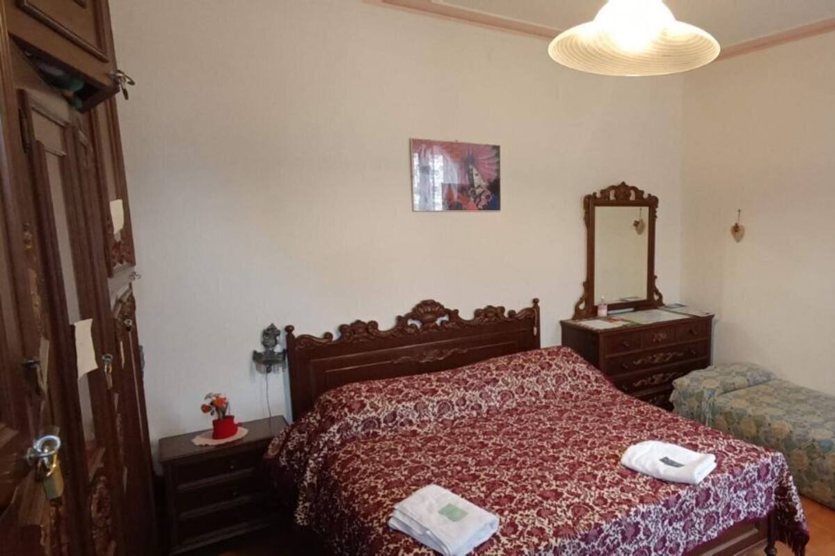 A bedroom with a large bed, a smaller bed, a dresser, a mirror, and a wardrobe.