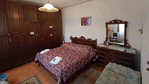 A bedroom with a wooden wardrobe, a bed with a patterned bedspread, a dresser with a mirror, and a small rug on the floor. - VENISERELAX (Mestre)