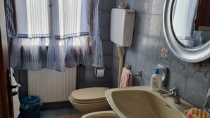 A bathroom with two toilets, a sink, a mirror, and a window with curtains. - VENISERELAX (Mestre)
