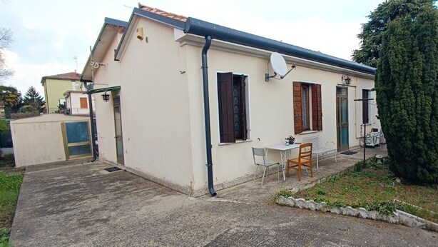 A single-story building with a small patio area, a satellite dish, and a tall coniferous tree. - VENISERELAX (Mestre)