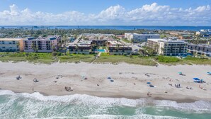 A beachfront hotel with multiple buildings, a sandy beach, and ocean waves. - Direct Oceanfront Condo on the Beach w/ Private Balcony, Heated Pool & Steps to Pier! (Cocoa Beach)