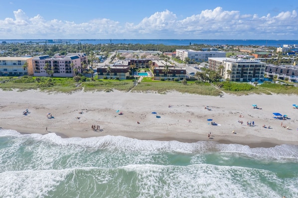 A beachfront hotel with multiple buildings, a sandy beach, and ocean waves.
