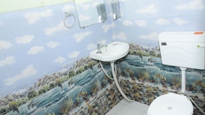 A bathroom with a sink, toilet, and a wall mural depicting a natural scene. - Hotel Sleep Inn    (Sonepat)