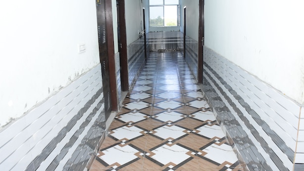 A hallway with patterned tiles, wooden doors, and a window at the end. - Hotel Sleep Inn    (Sonepat)