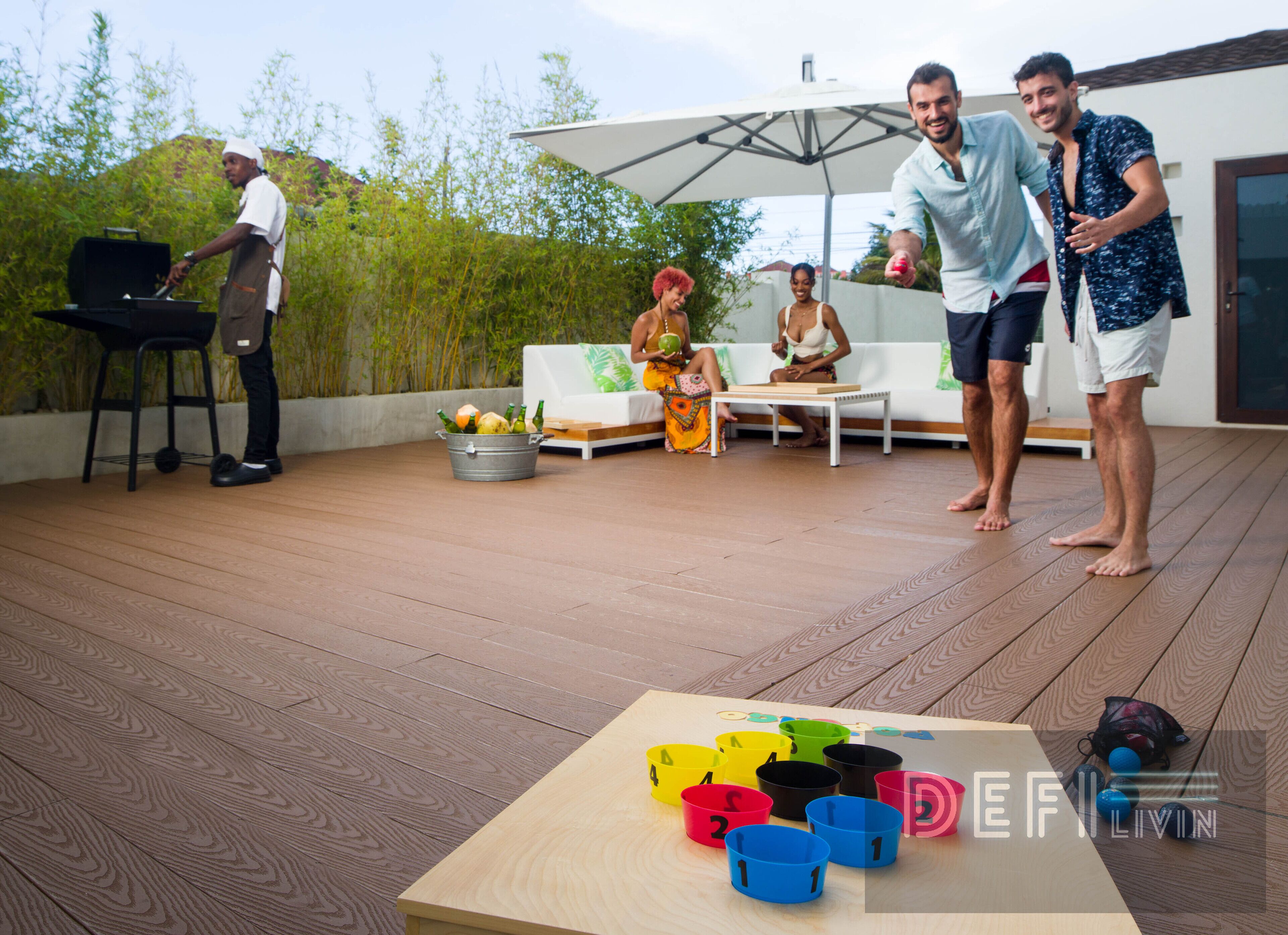 A wooden deck with a grill, outdoor seating, and a table with numbered cups.