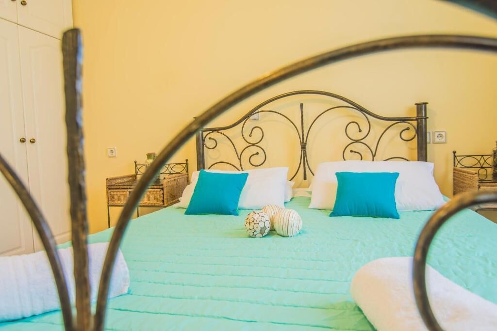 Ein Bett mit Metallkopfteil, zwei Kissen und einer grünen Tagesdecke.
