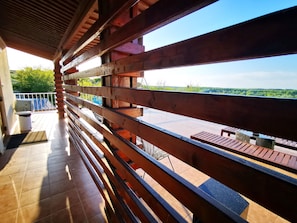 A wooden balcony with a view of a green landscape. - Pensiunea 4 Salcii (Bestepe)