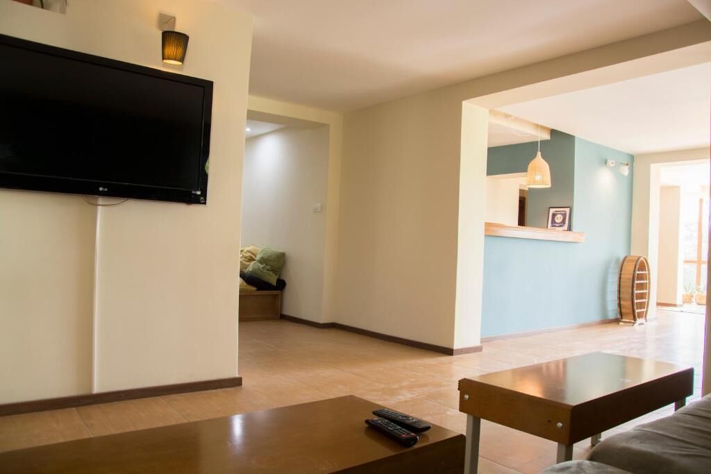 Una sala de estar con televisión de pantalla plana montada en la pared, una mesa de centro y un sofá.