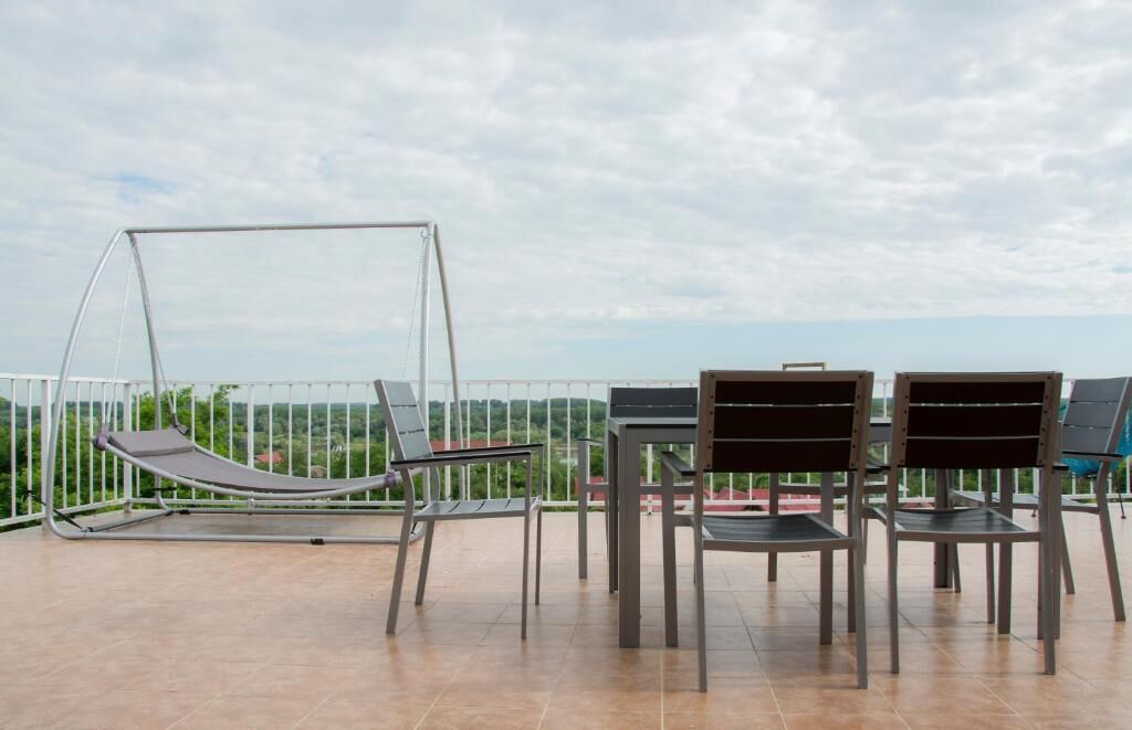 A balcony with a swing, two chairs, and a table.