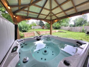 A hot tub under a covered patio with a wooden roof, surrounded by a backyard with a wooden fence and greenery. - 8 Min to Airport & Mall of America, Central,  Spacious, Many Amenities! (Minneapolis)