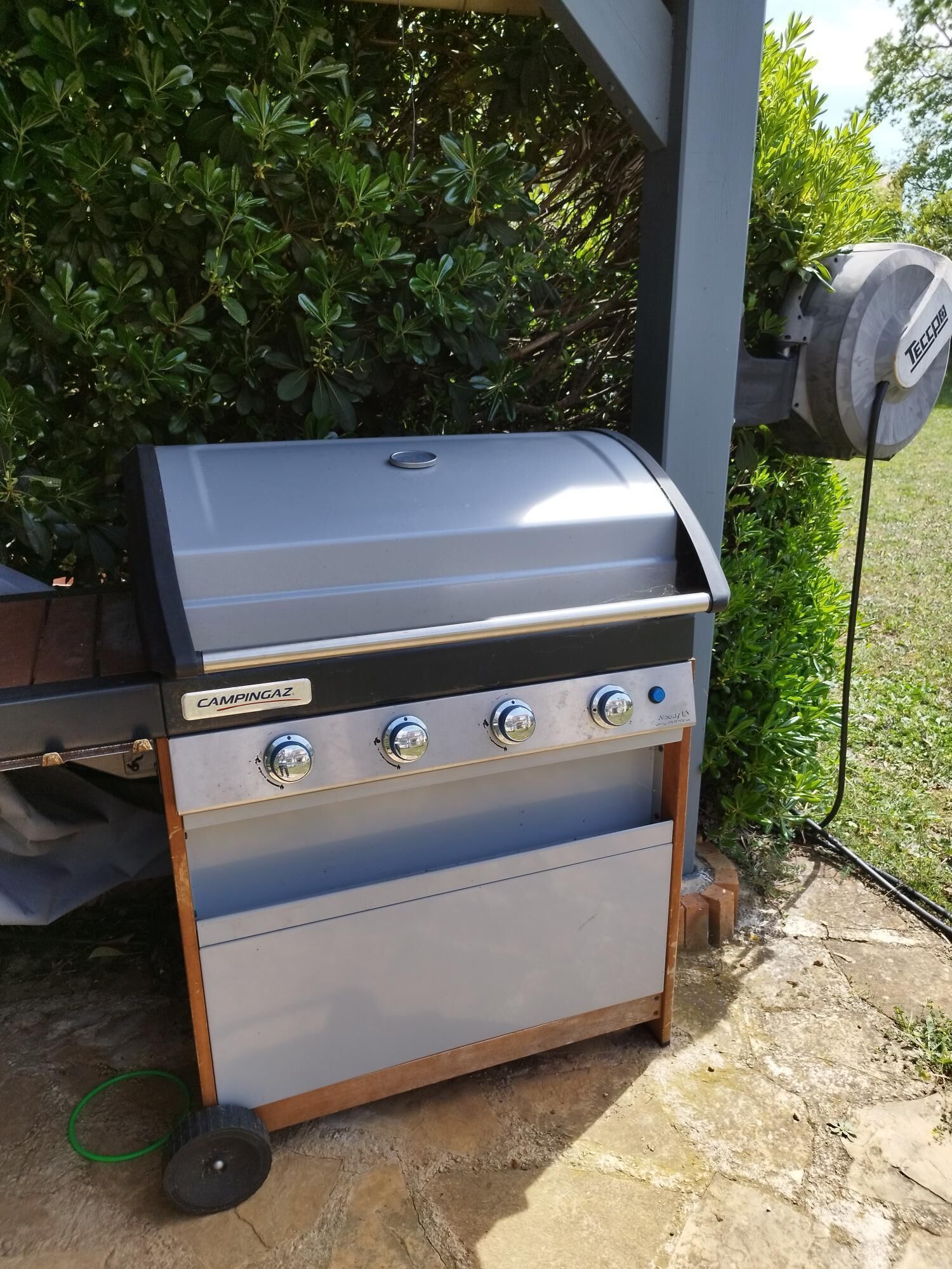 Ein tragbarer Campinggrill mit vier Brennern, einer seitlichen Schublade und einem angebrachtem Starter für den Schornstein.
