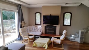 Ein modernes Wohnzimmer mit Kamin, bequemen Sitzgelegenheiten und einem großen Fernseher.