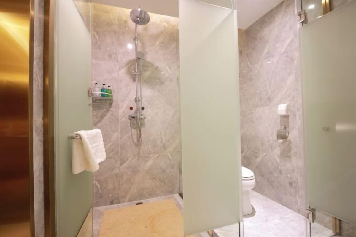 A modern bathroom with a glass-enclosed shower, a toilet, and a marble floor.