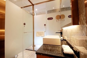 A modern bathroom with a glass shower enclosure, a marble countertop, and a large mirror. - Kaye Hotel (Liuzhou)