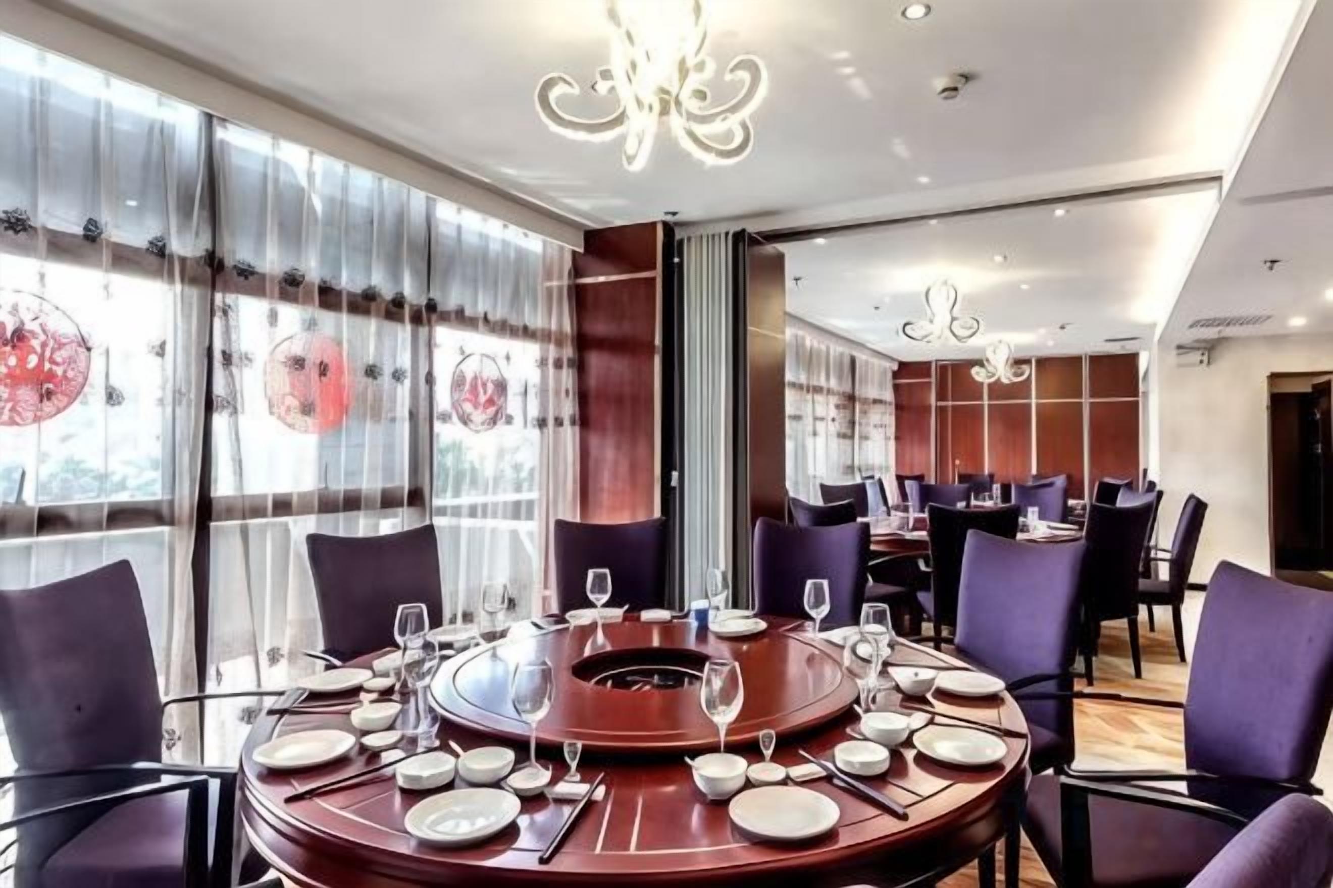 A dining area with round tables, chairs, and a central fire feature.