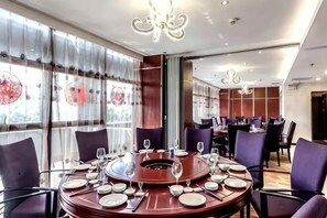A dining area with round tables, chairs, and a central fire feature. - Kaye Hotel (Liuzhou)