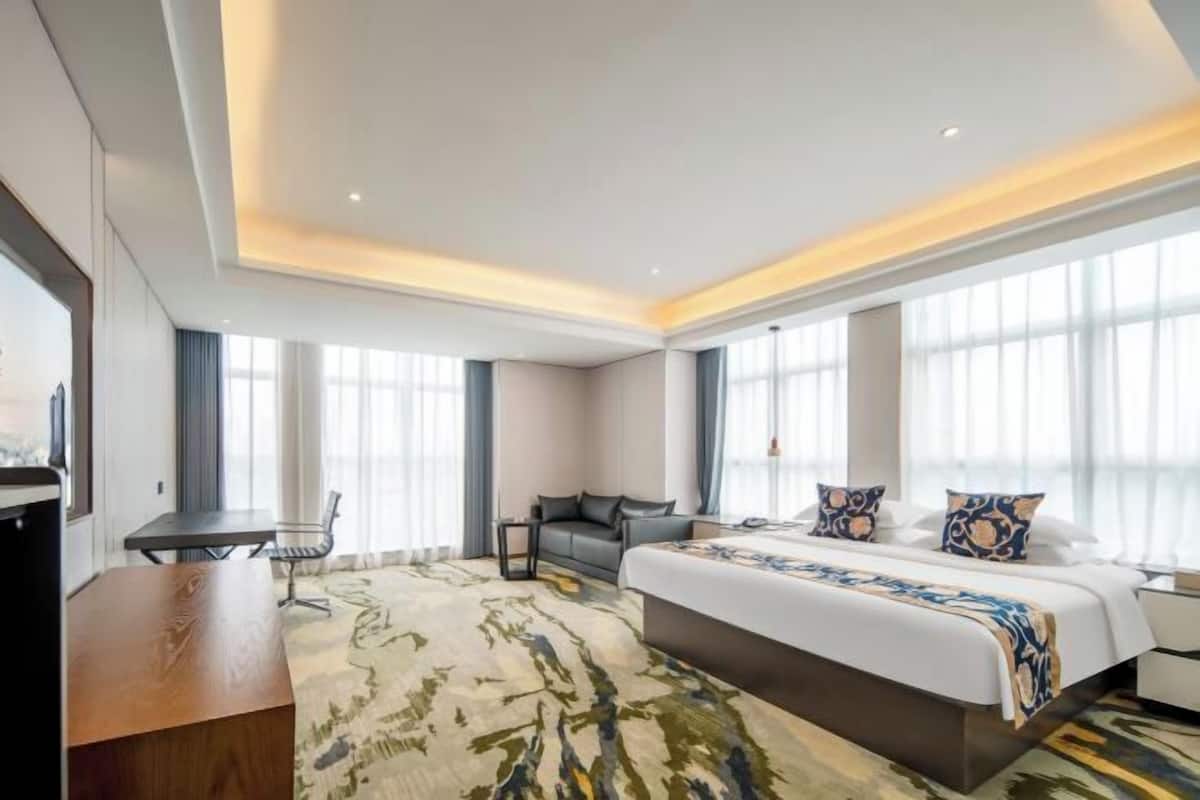 A modern hotel room with a large bed, a desk, and a chair.