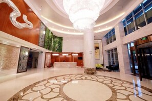 A spacious lobby with a central chandelier, a reception desk, and a large column. - Kaye Hotel (Liuzhou)