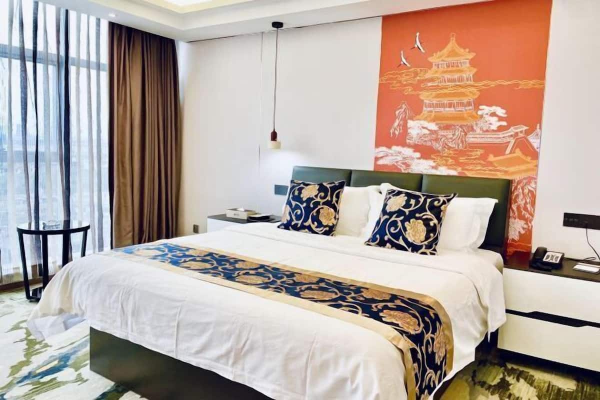 A hotel room with a large bed, a nightstand, a telephone, and a wall with a large painting.