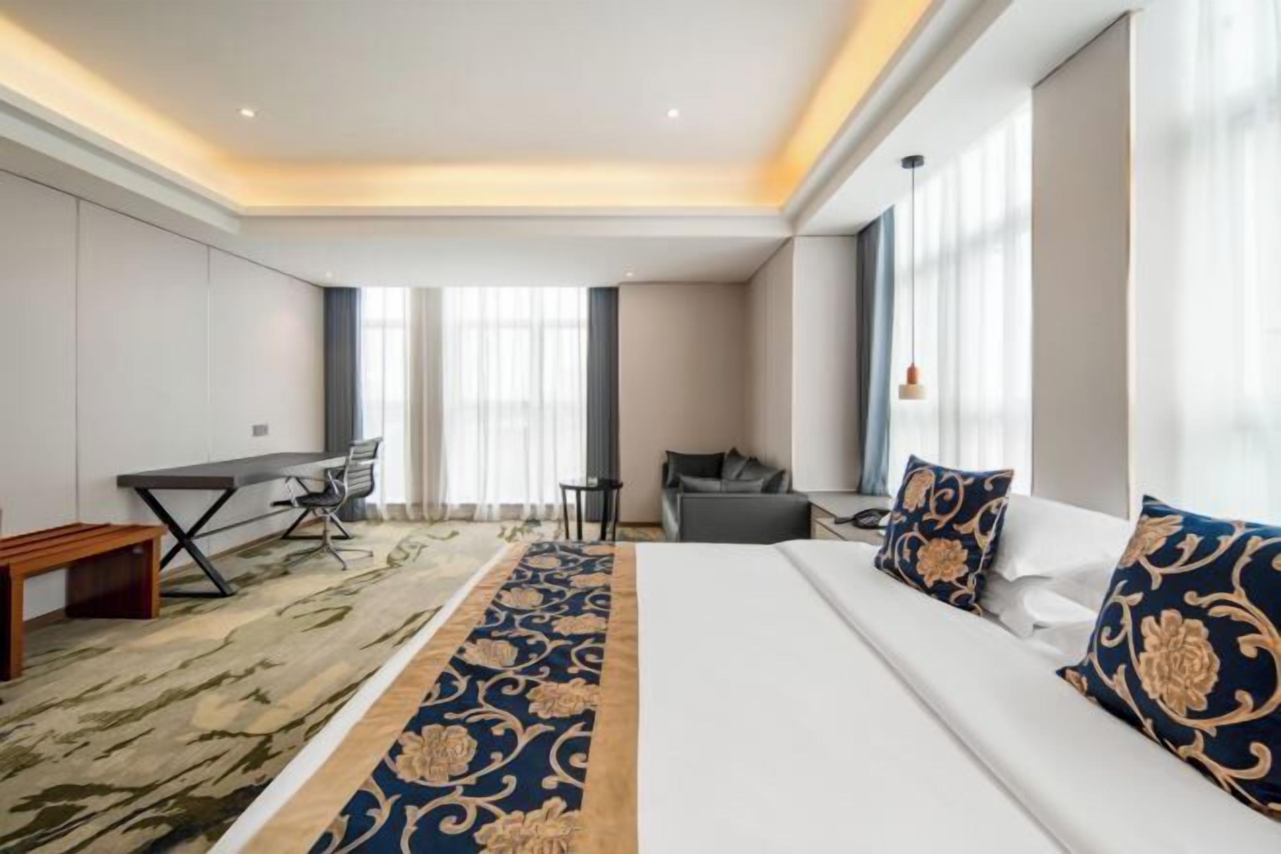 A hotel room with a large bed, a desk, a sofa, and a small table.