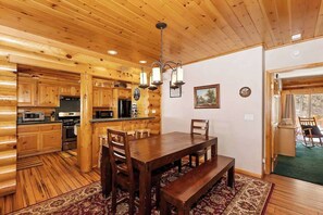 L’intérieur d’un chalet en bois comprend un coin repas, une cuisine et une grande fenêtre.