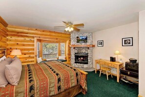 Une pièce aménagée dans le style d’un chalet en rondins, avec un lit, un bureau, une cheminée et un téléviseur.