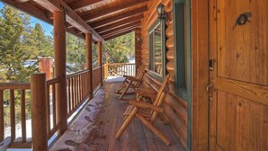 A wooden porch with a covered area, wooden railings, and a door.