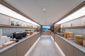 Une cuisine moderne dotée d’un îlot central, d’appareils électroménagers en acier inoxydable et de boîtes de rangement pour aliments disposées de manière ordonnée.