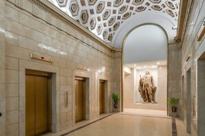 Experience the grandeur of a classic lobby with a polished floor, decorative ceiling, and elegant statue.