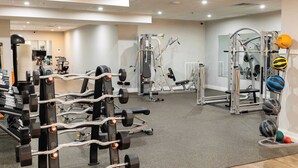A well-lit gym with various exercise equipment, including weight machines and free weights. - Sosuite | 2BR Apt w W/D, Gym, Lounge (Philadelphia)