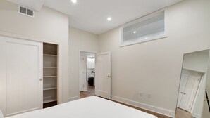 A bedroom with a large bed, a closet, and a view of the kitchen. - Sosuite | 2BR Apt w W/D, Gym, Lounge (Philadelphia)