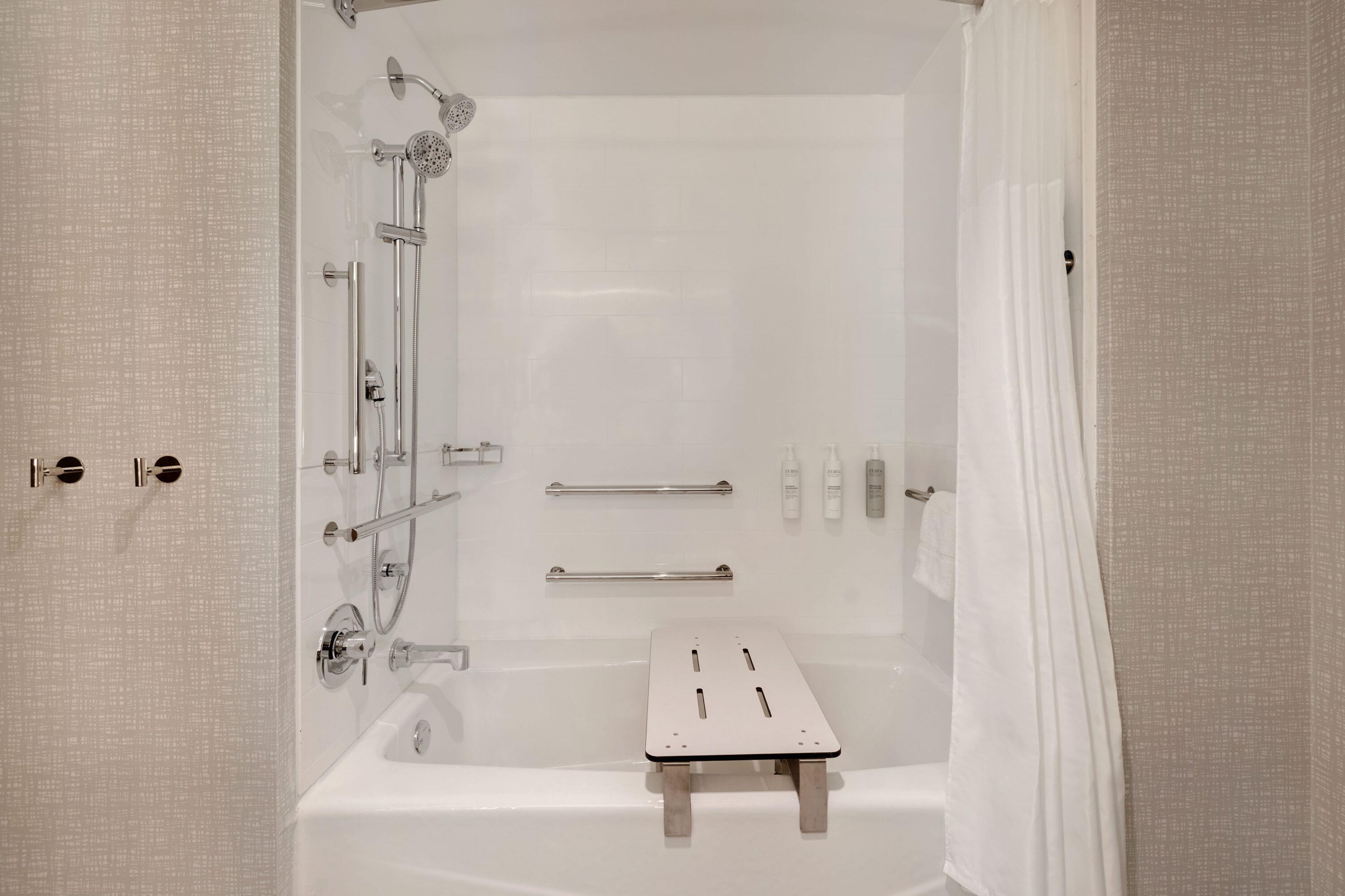 Un baño moderno con bañera, ducha y un pequeño taburete de madera.