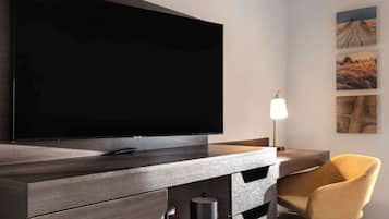 A modern room with a flat-screen TV mounted on a wooden cabinet, a yellow chair, and a lamp.
